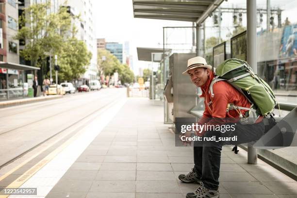 asian traveler man waiting for the bus - melbourne train stock pictures, royalty-free photos & images