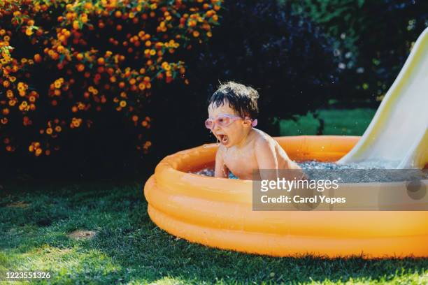 little boy having fun in inflatable pool - extreem weer stock pictures, royalty-free photos & images
