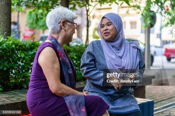 senior chinese lady having conversation with malay friend outdoors - deep conversation stock pictures, royalty-free photos & images