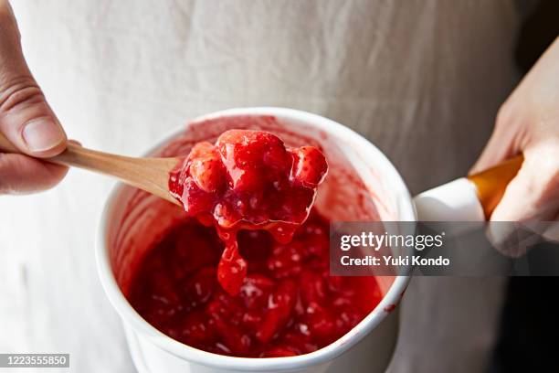 scoop the strawberry jam in the pan with a spoon - marmelade stock-fotos und bilder