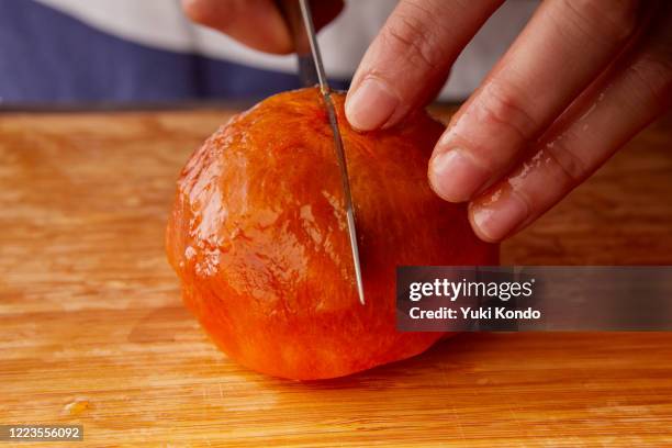 cut the persimmons with a knife. - persimone stock-fotos und bilder