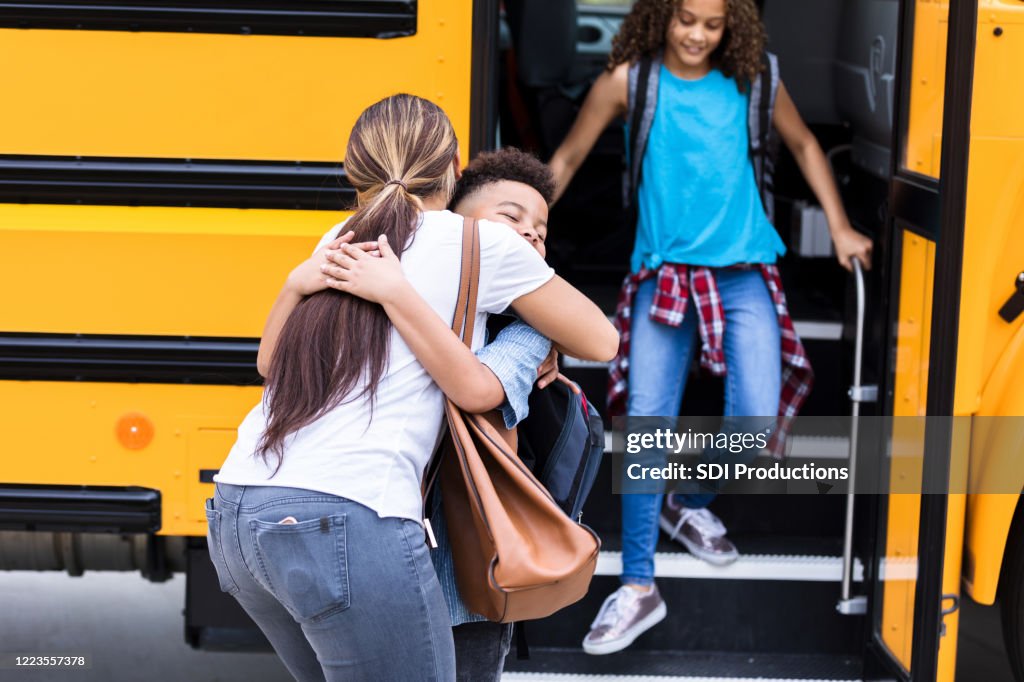 As daughter gets off bus, mom hugs son