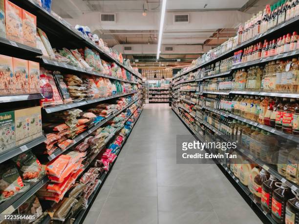 interior del supermercado lleno de artículos de comestibles en filas con estante mostrado - supermercado fotografías e imágenes de stock