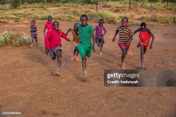 african children chasing each other on savannah in a village near mount kilimanjaro, east africa - east africa imagens e fotografias de stock