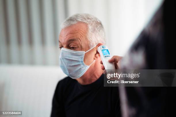 covid-19 health officer taking temperature of men attending - thermometer turkey stock pictures, royalty-free photos & images