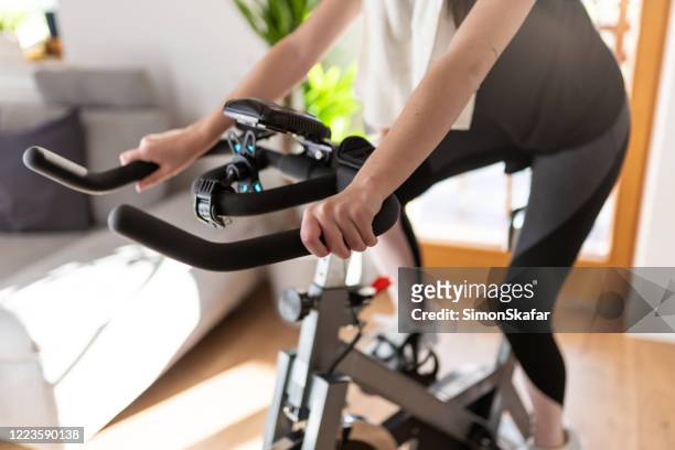 自宅でエクササイズバイクの女性トレーニングの低いセクション - cardio ストックフォトと画像