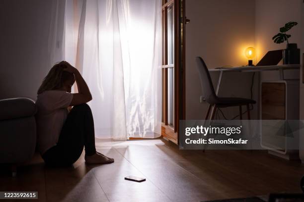 triste mujer deprimida llorando en casa. habitación oscura. - presión fotografías e imágenes de stock