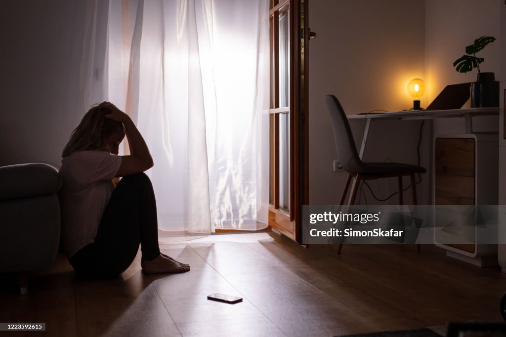 Triste donna depressa che piange a casa. Stanza buia.