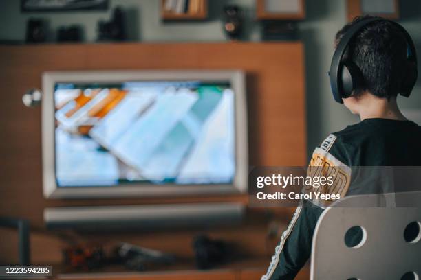boy enjoying game console at home.natural light - boy at television stockfoto's en -beelden