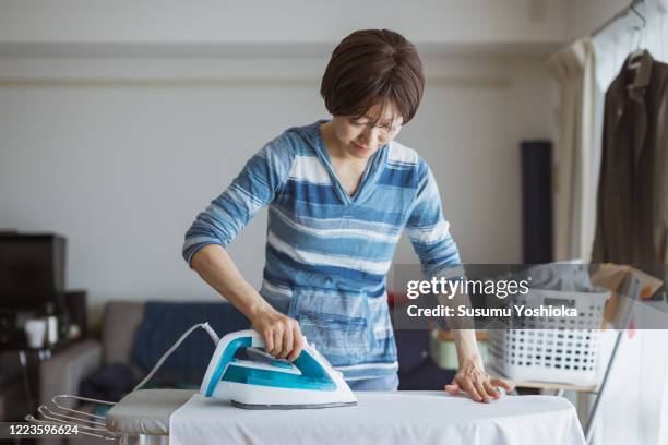 housewife ironing a shirt - iron appliance stock-fotos und bilder