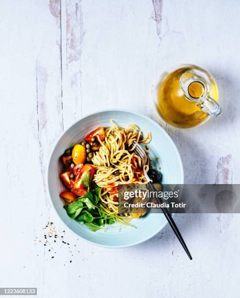 bowl of spaghetti with basil, tomatoes and olives on white, wooden background - olive oil bowl stock pictures, royalty-free photos & images