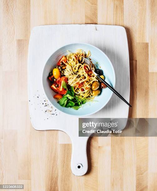 bowl of spaghetti with basil, tomatoes and olives on wooden background - parmesan cheese overhead stock pictures, royalty-free photos & images