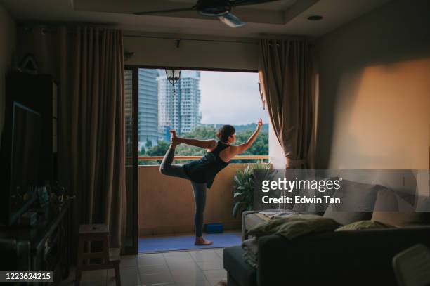 an asian chinese mid adult woman practicing yoga in her balcony
