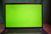 Close up laptop with green screen on table in work space concept.
