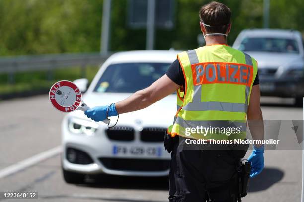 German border police officer stops cars in a checkpoint of the D87 road at the German-French border during the coronavirus crisis on May 8, 2020 near...