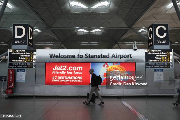 Passenger walks through departures at Stansted Airport on June 30, 2020 in Stansted, United Kingdom. Passengers travelling between the UK and some...