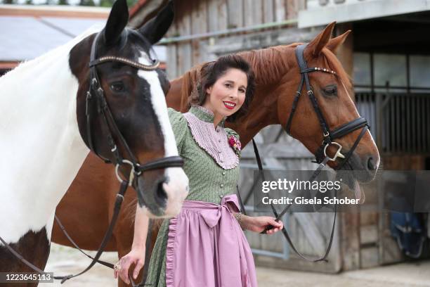 Dirndl fashion designer Lola Paltinger poses with her horses Casper and Woopty during a photo shooting to present her new Dirndl collection on June...