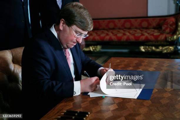 Mississippi Republican Gov. Tate Reeves signs the bill retiring the last state flag in the United States with the Confederate battle emblem, at the...