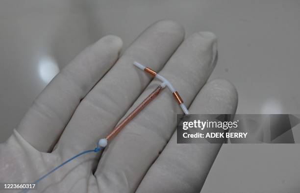 This picture taken on June 25, 2020 shows a doctor holding an IUD birth control device to put into a patient's womb at a clinic in Jakarta. -...