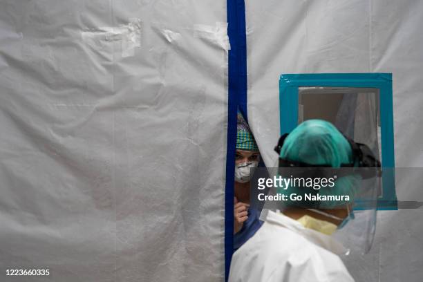Medical staff talk through the air tight curtain in the Covid-19 intensive care unit at the United Memorial Medical Center on June 30, 2020 in...