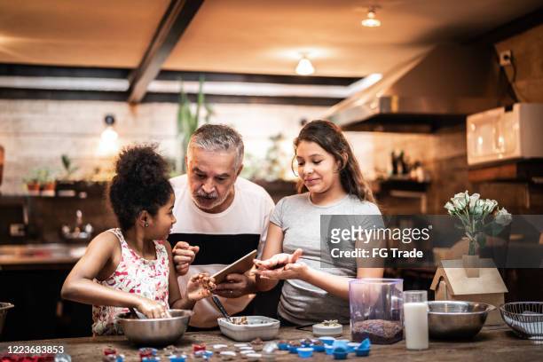 grandfather teaching their grandchild how to prepare brazilian brigadeiro - cool house stock pictures, royalty-free photos & images