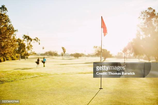 golfers walking toward green during early morning golf game - golfer walking stock pictures, royalty-free photos & images