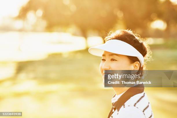 portrait of smiling mature woman during round of golf - mature asian woman candid foto e immagini stock