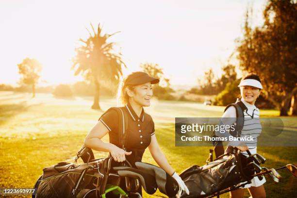 laughing woman walking on fairway while playing golf with mother - female golf stockfoto's en -beelden