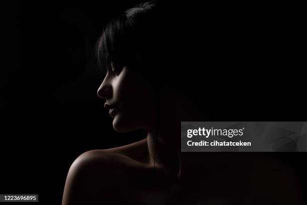 verticale de profil de jeune femme contre le fond noir - belle peau photos et images de collection