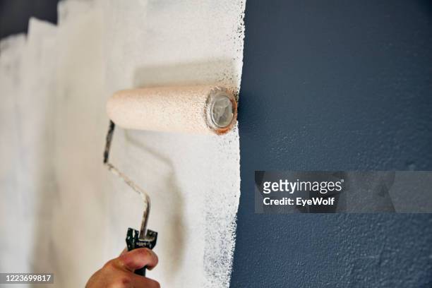 close up on a pain roller spreading paint on a wall. - wand streichen stock-fotos und bilder