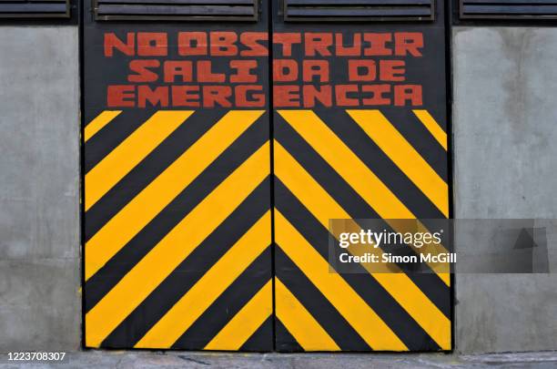 emergency exit doors with spanish-language warning sign: 'no obstruir. salida de emergencia.' (do not obstruct. emergency exit.) - obstruir stock pictures, royalty-free photos & images