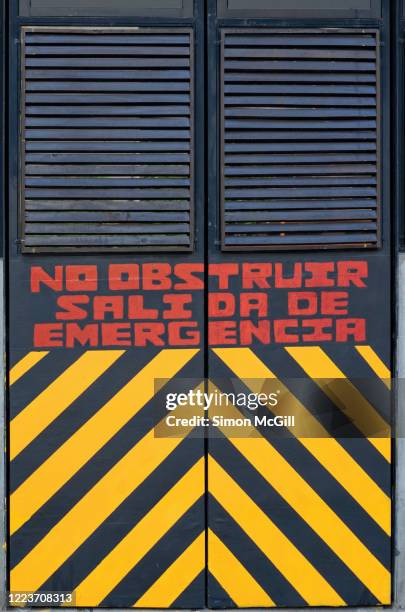 emergency exit doors with spanish-language warning sign: 'no obstruir. salida de emergencia.' (do not obstruct. emergency exit.) - obstruir stock pictures, royalty-free photos & images