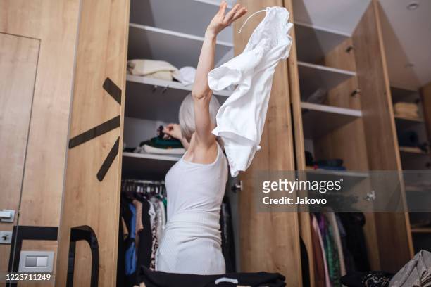 frau reorganisiert ihre garderobe in ihrem schlafzimmer - entrümpeln stock-fotos und bilder