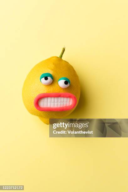 happy lemon fruit with face on yellow background - saftpresse stock-fotos und bilder