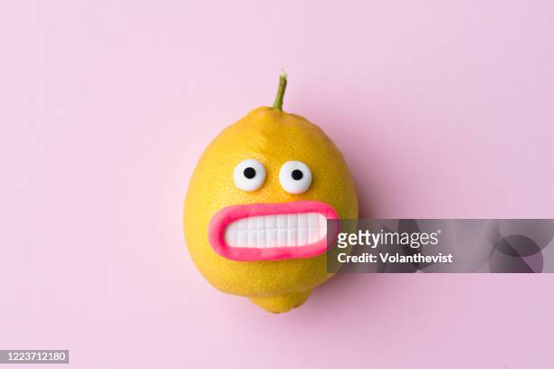 happy lemon fruit with face on pink background - comic augen stock-fotos und bilder