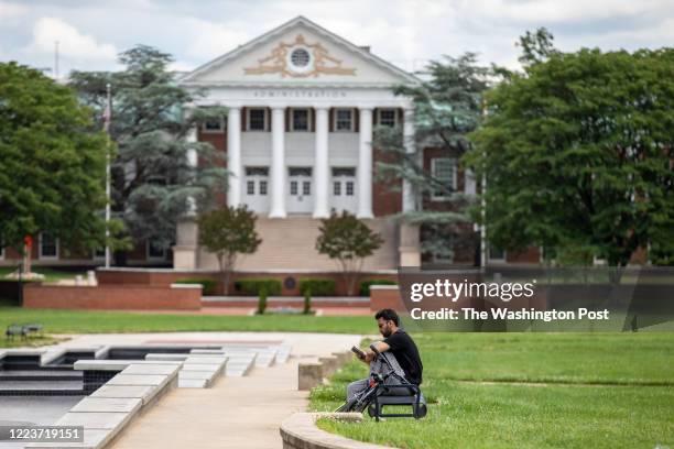 Man sits on the McKeldin Mall, a large grassy area at the University of Maryland campus in College Park, Maryland on Sunday, June 21, 2020.
