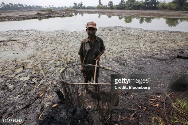 Fisherman holds a fishing net on the crude oil polluted shoreline in Goi, Nigeria, on Friday, Jan. 31, 2020. Nigerians from the delta are now asking...