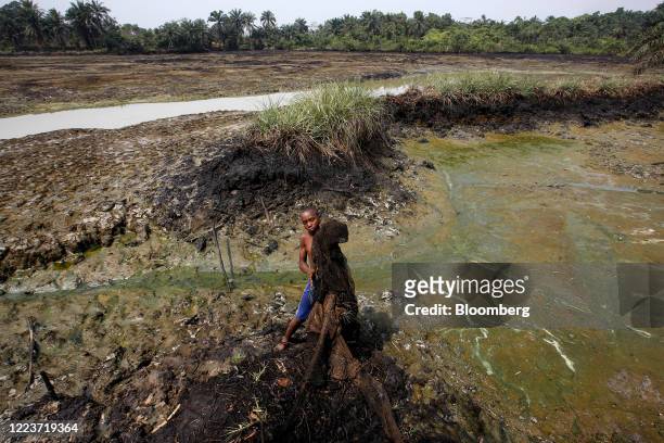 Boy holds up an oil stained fishing net from polluted fishing pond waters in Goi, Nigeria, on Saturday, Feb. 1, 2020. Nigerians from the delta are...
