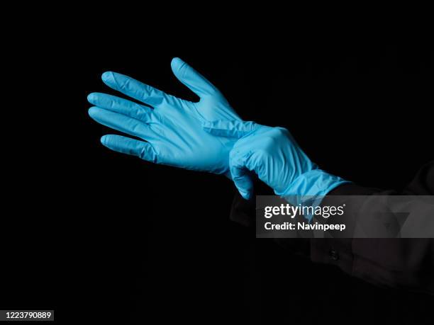 hands wearing protective blue gloves - blauer handschuh stock-fotos und bilder