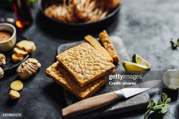 zubereitung eines veganen gerichtes mit tempeh - fleischersatz stock-fotos und bilder