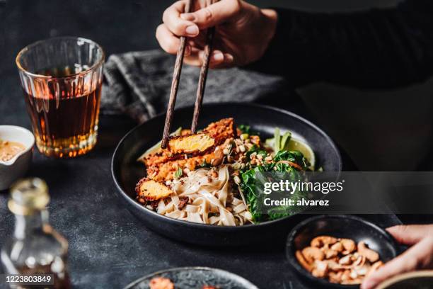 frau isst frisch zubereitete asiatische vegane mahlzeit - fleischersatz stock-fotos und bilder