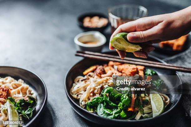 chef fügt einem veganen gericht limetten hinzu - sojabohnensprosse stock-fotos und bilder
