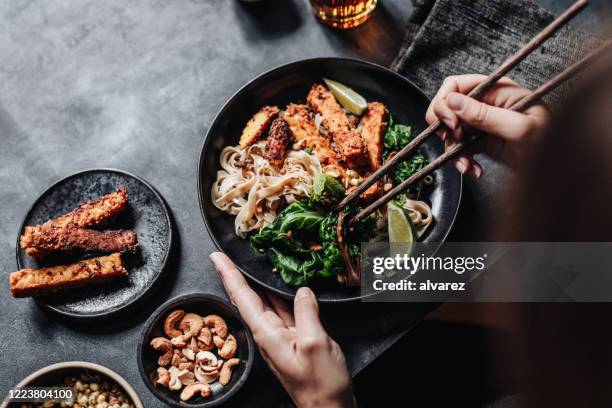 frau essen asiatische gericht mit essstäbchen - asiatische küche stock-fotos und bilder