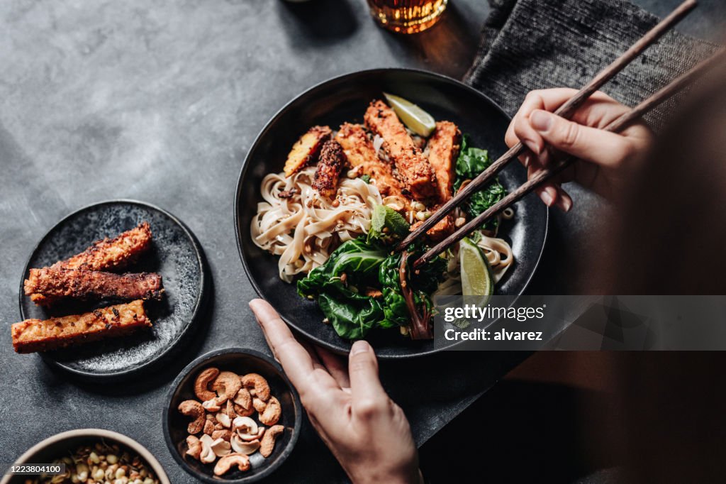 アジア料理を箸で食べる女性