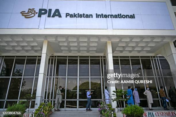 People stand in queue as they wait their turn to buy flight tickets outside Pakistan International Airlines office in Islamabad on July 1, 2020. -...