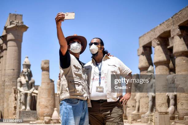 Mask-clad tour guides pose together for a "selfie" on a cell phone at the colonnade of the ancient Temple of Luxor in Egypt's southern city of Luxor...