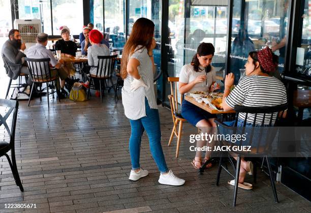 Israeli settlers have their breakfast at a cafe in the West Bank settlement of Ariel, on July 1, 2020. - The government of Israeli Prime Minister...