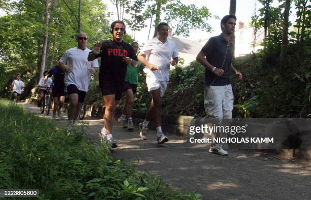 French President Nicolas Sarkozy waves to journalists during his morning jog in Wolfeboro, New Hamphire, where he is vacationing 17 August 2007....