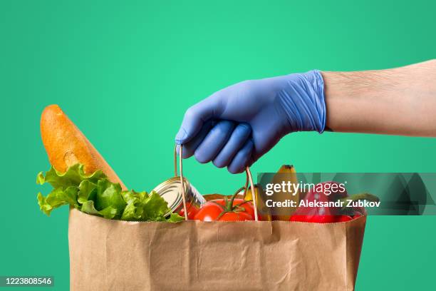 in the person's hand is a paper bag with food. donation and home delivery. - food donation stock pictures, royalty-free photos & images