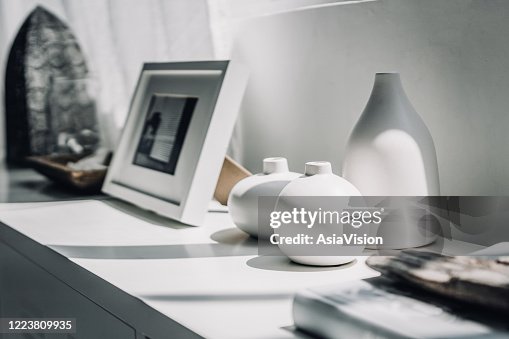Décoration à la maison des vases neutres colorés et cadre d’image sur une armoire par la fenêtre dans la lumière du soleil Décoration à la maison des vases neutres colorés et cadre d’image sur une armoire par la fenêtre dans la lumière du soleil